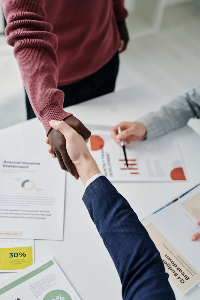 gallery-5 Professional handshake over financial documents symbolizes successful business partnership and teamwork.